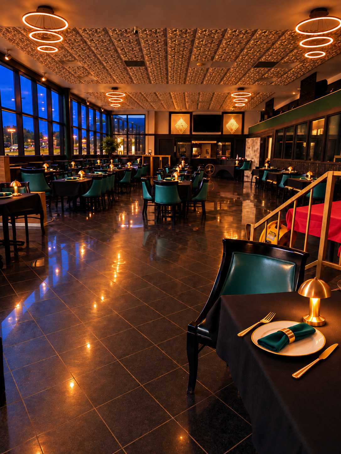 Emerald Lounge with evening lighting and styling: illuminated ring fixtures, a rear bar and chandeliers, emerald napkins, gold rings and separate gold cutlery